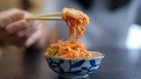 Korejski kimchi u plavoj zdjeli s chopsticks štapićima