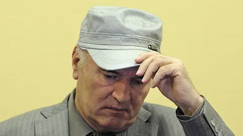 Portret Ratka Mladića u sivoj kapi i odelu, s rukom na čelu