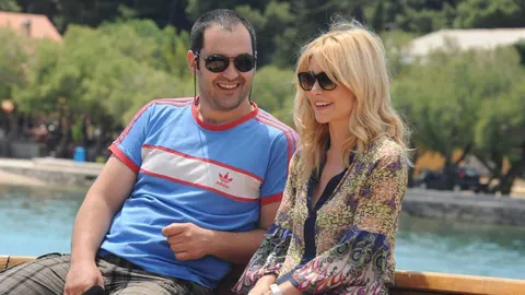 Muškarac u plavoj majici i žena u šarenoj bluzi sjede na brodu