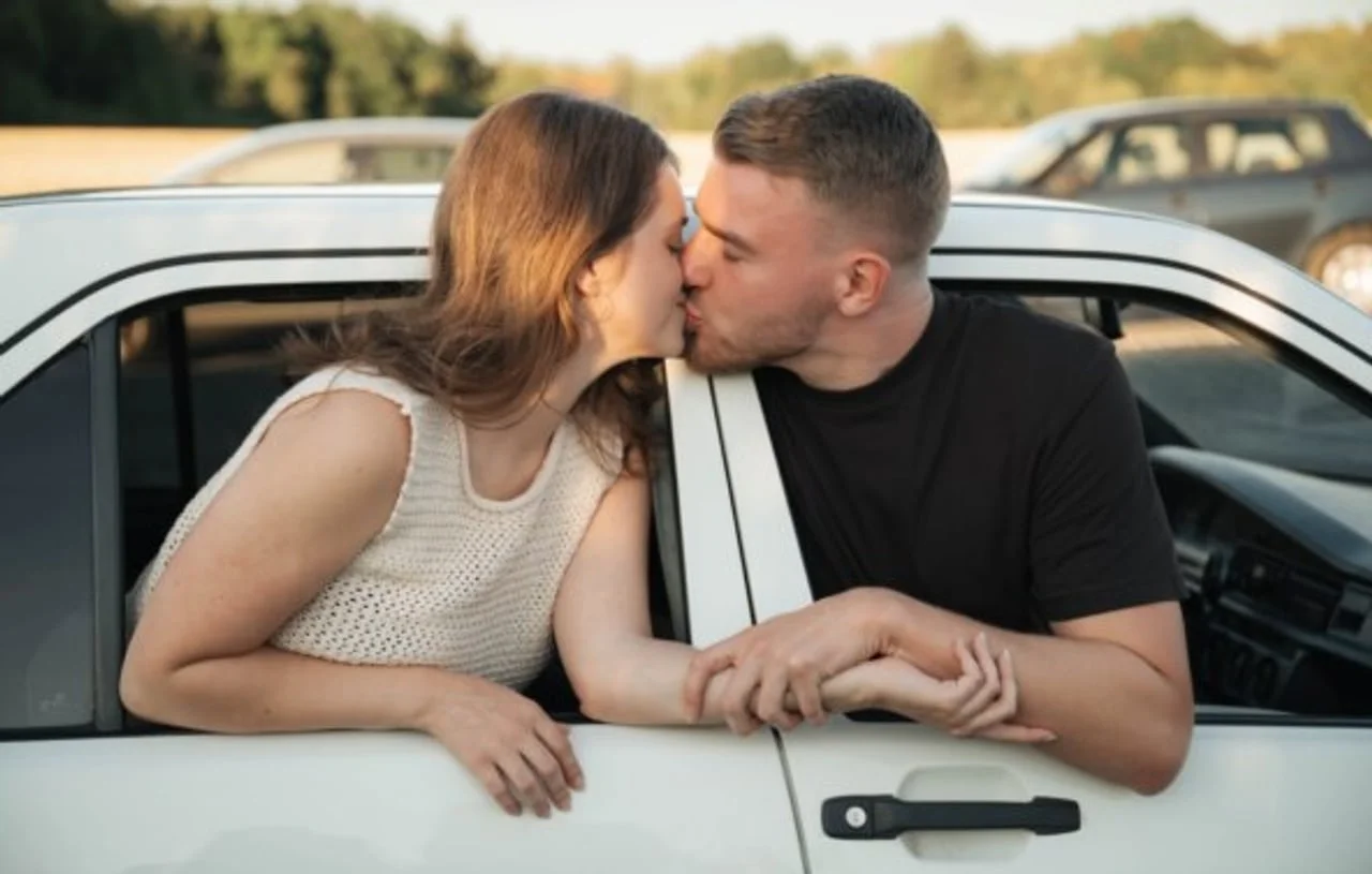 Par koji se ljubi naslonjeni na bijeli automobil u prirodi