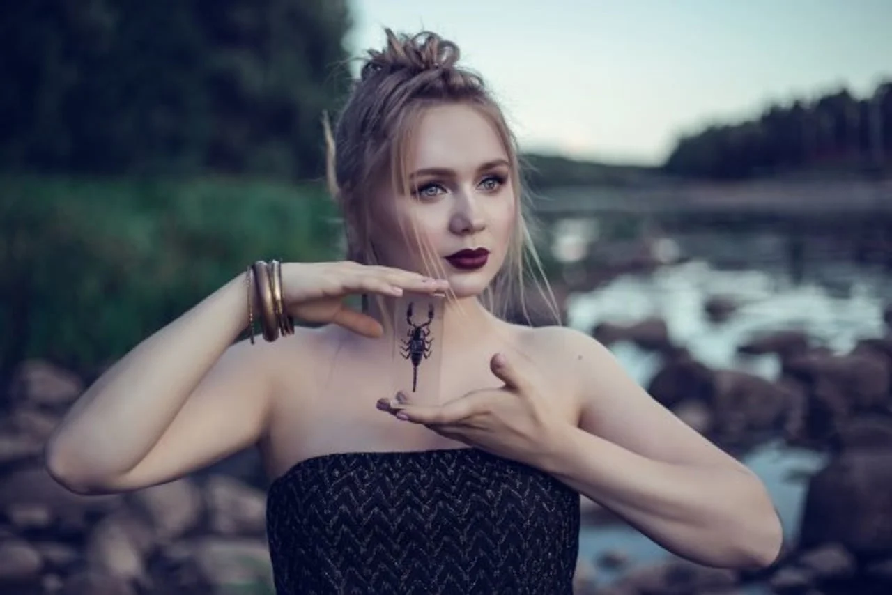 Žena pored rijeke koja drži prozirnu pločicu s motivom škorpiona