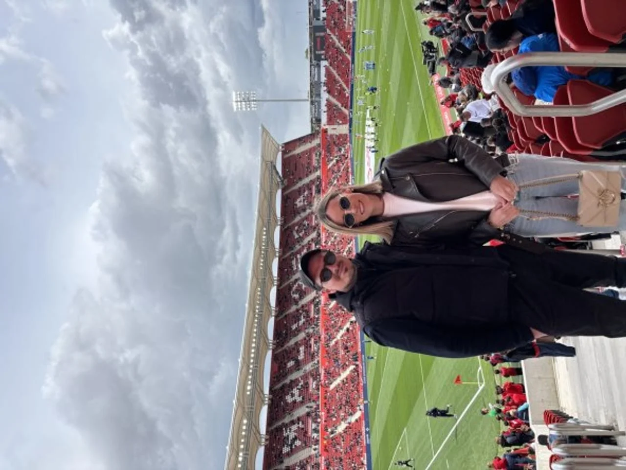 Muškarac i žena u crnim jaknama na tribinama nogometnog stadiona