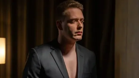 Portret mladog muškarca u tamnom odjeću s ozbiljnim izrazom lica