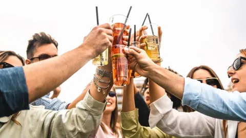 Grupa ljudi nazdravlja čašama punim obojenih alkoholnih pića i koktela