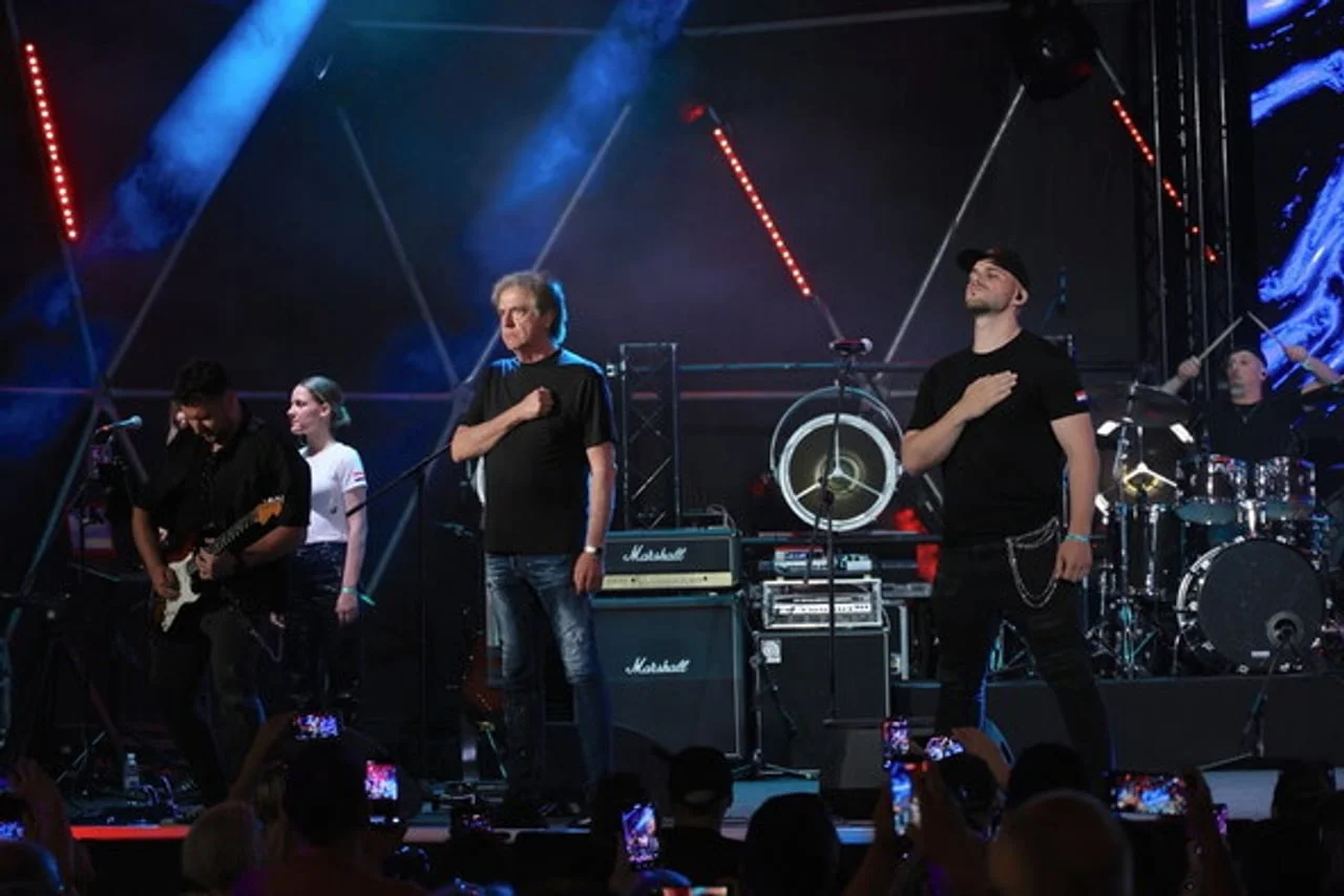 Glazbenici na koncertnoj pozornici s instrumentima i plavim svjetlima