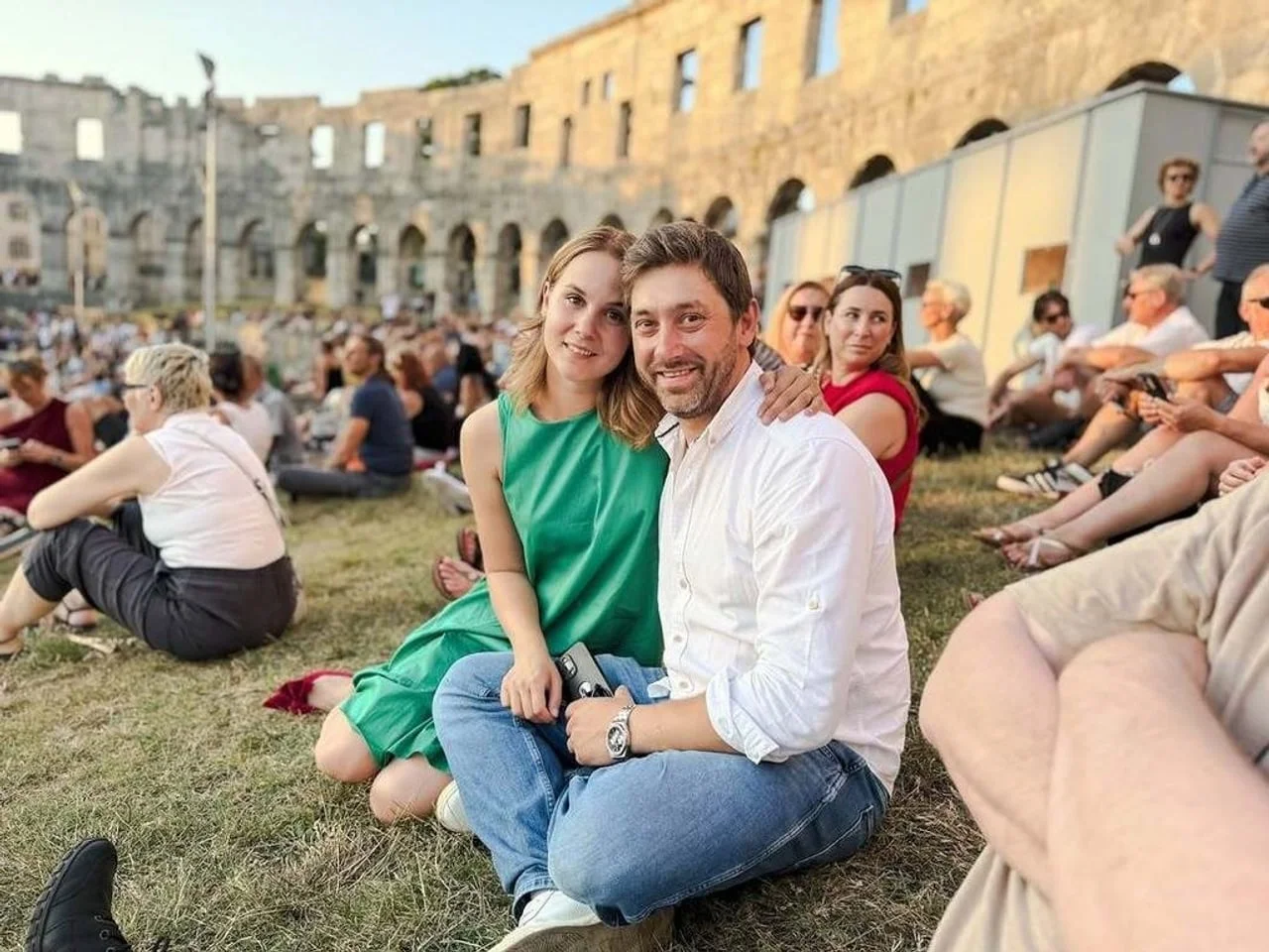 Nasmijani Nevena i Marko Vukes sjede na travi ispred amfiteatra u Puli.