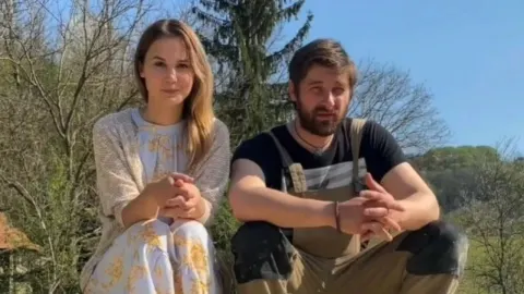 Nevena i Marko Vukes sjede na otvorenom ispred drveća tijekom sunčanog dana.