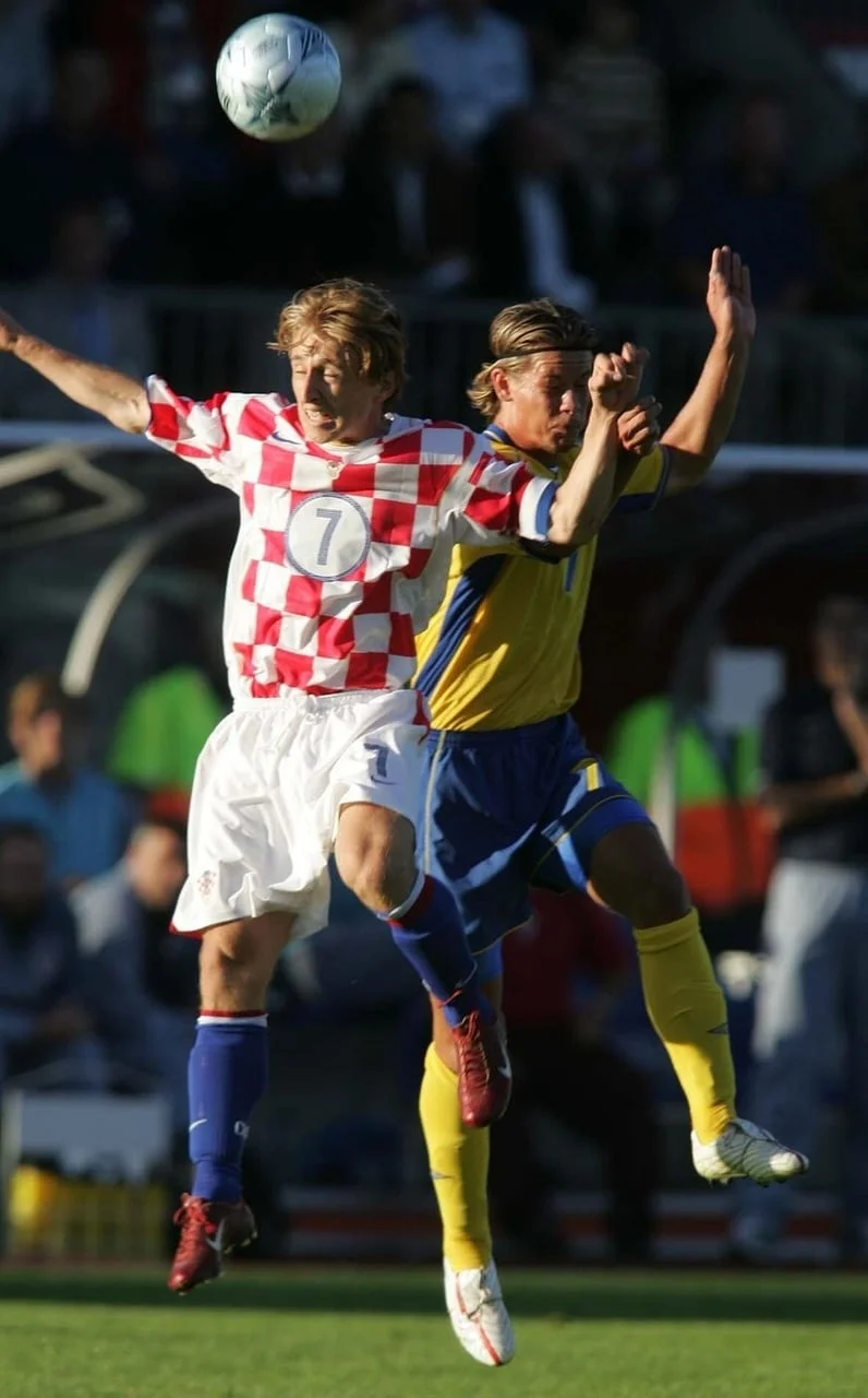Mladi Modrić u crveno-bijelom dresu skače za loptu u duelu