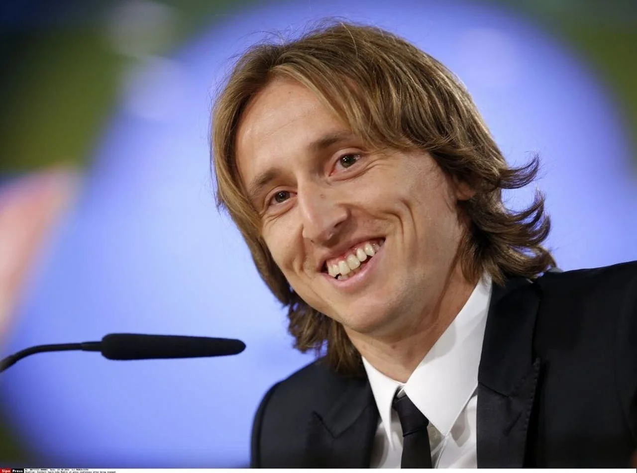 Nasmijani Luka Modrić u crnom odelu za mikrofonima