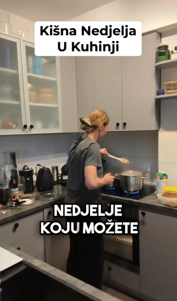 Žena koja priprema jelo u modernoj sivoj kuhinji