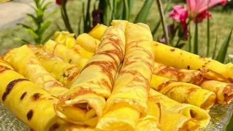 Tanjir pun zlatno rumenih, zarolanih palačinki na otvorenom