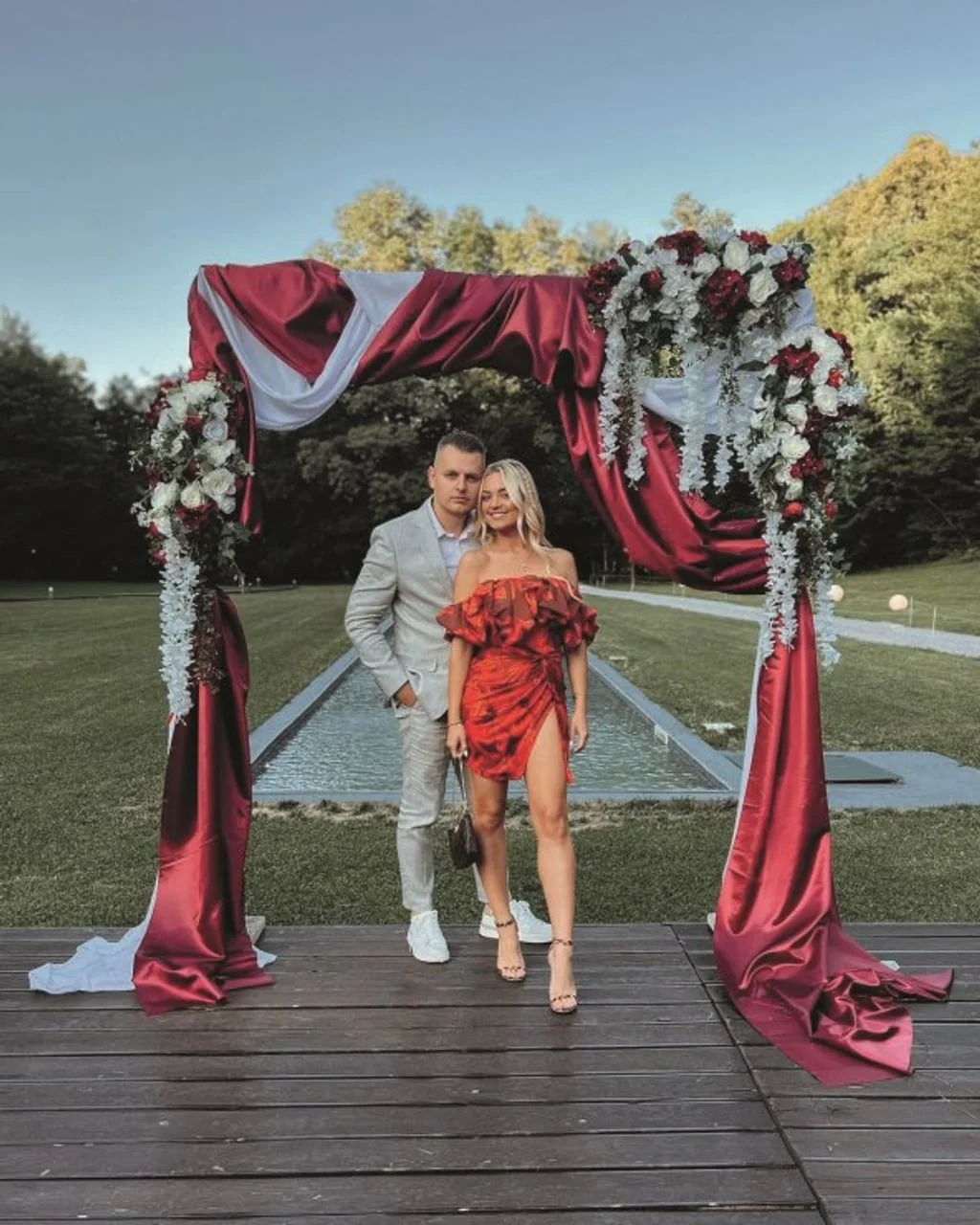 Maja Šuput i njezina partner Matija poziraju pod crvenim cvjetnim lukom
