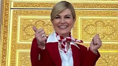 Kolinda Grabar-Kitarović u crvenom saku i marami ispred zlatnih vrata