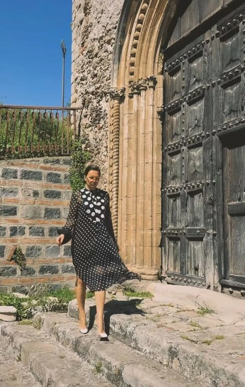 Nina Badrić u haljini na točkice pored velikih drvenih vrata crkve