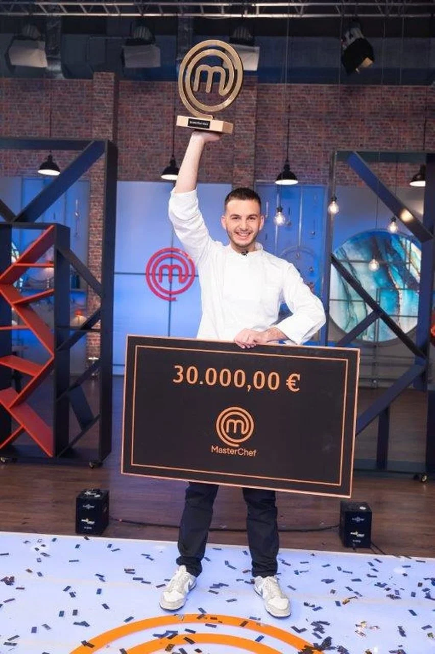 Muškarac u kuharskoj jakni drži zlatni trofej i veliki ček od 30.000 eura