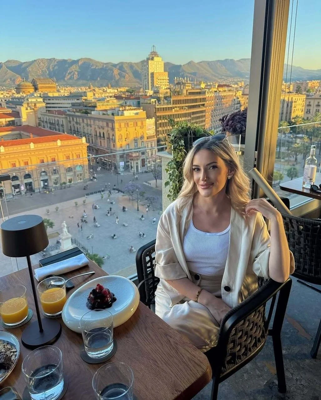 Portret žene u svijetlom odjeću s urbanim pejzažom u pozadini