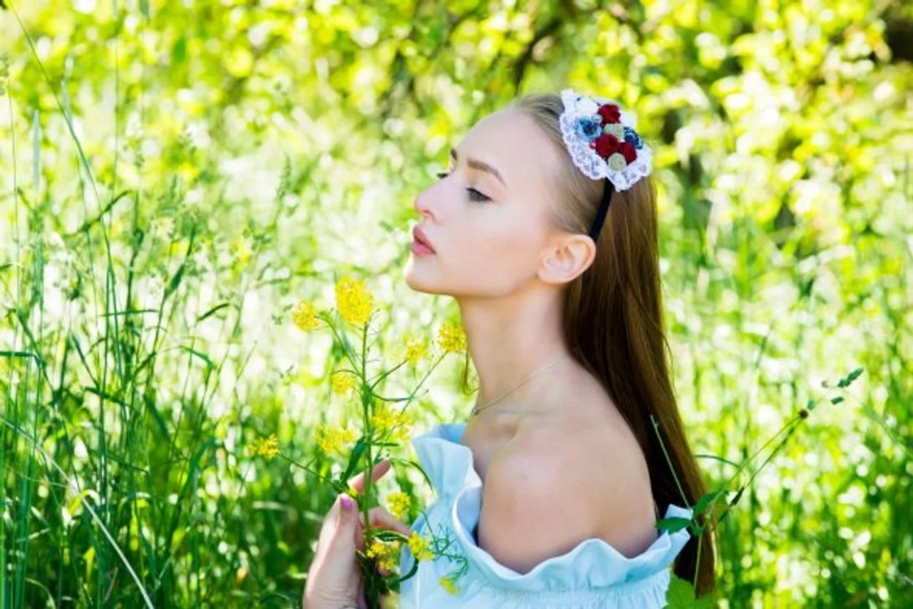 Mlada žena s cvjetnim vijencem u kosi koja stoji u zelenom presumptionu