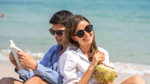 Sretan par u sunčnim naočalama koji uživa na pješčanoj plaži