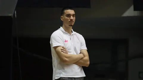 Mladi muškarac u bijeloj polo majici s prekrštenim rukama