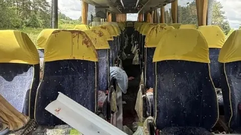 Unutrašnjost oštećenog autobusa s plavim sjedalima i žutim naslonima