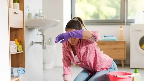 Umorna žena s ljubičastim rukavicama u kupaonici