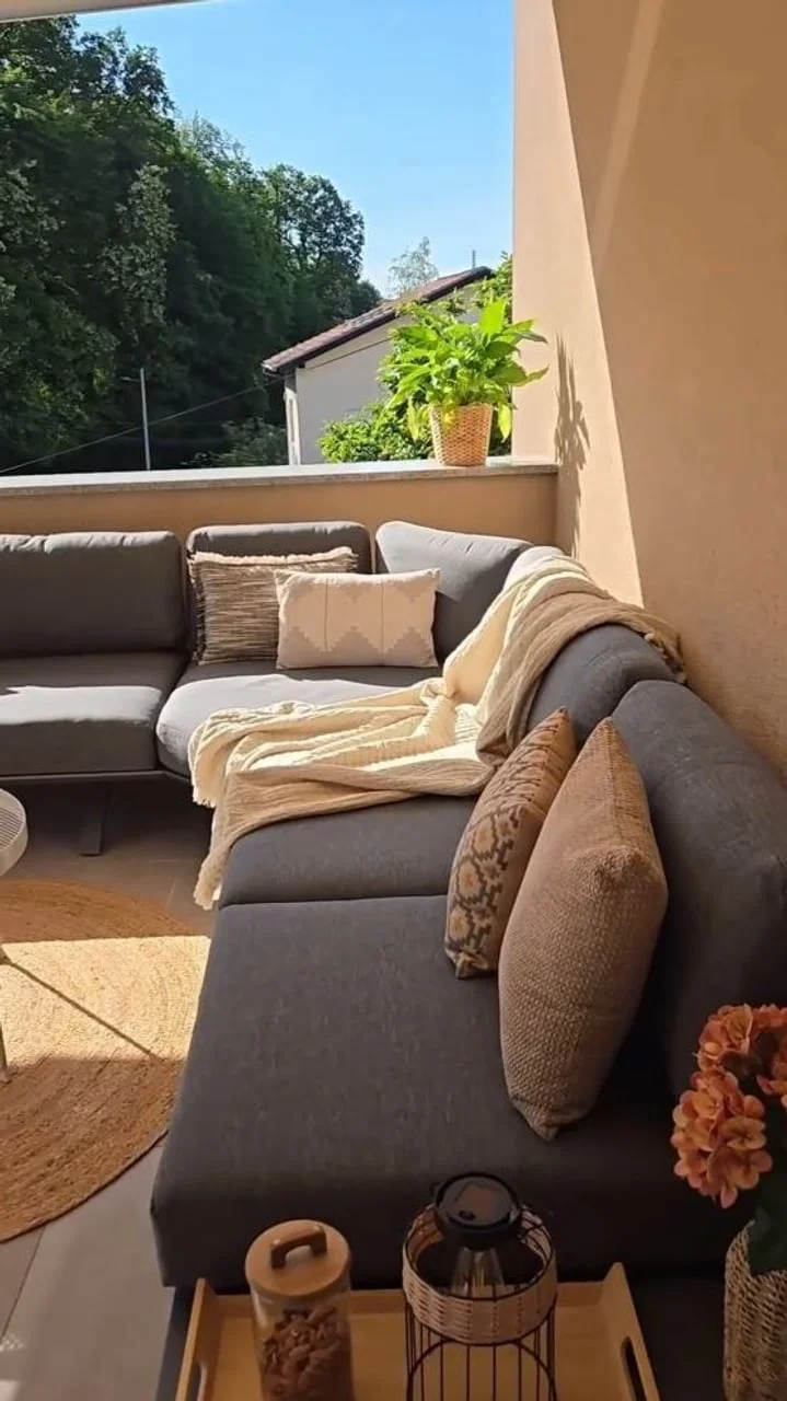 Sivi vanjski kaučac s jastucima na sunčanom terasu