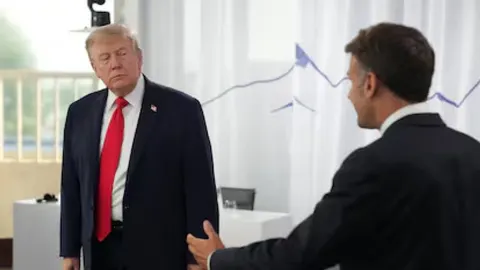 Donald Trump u tamnom odelu i crvenoj kravati stoji nasuprot drugog muškaraca