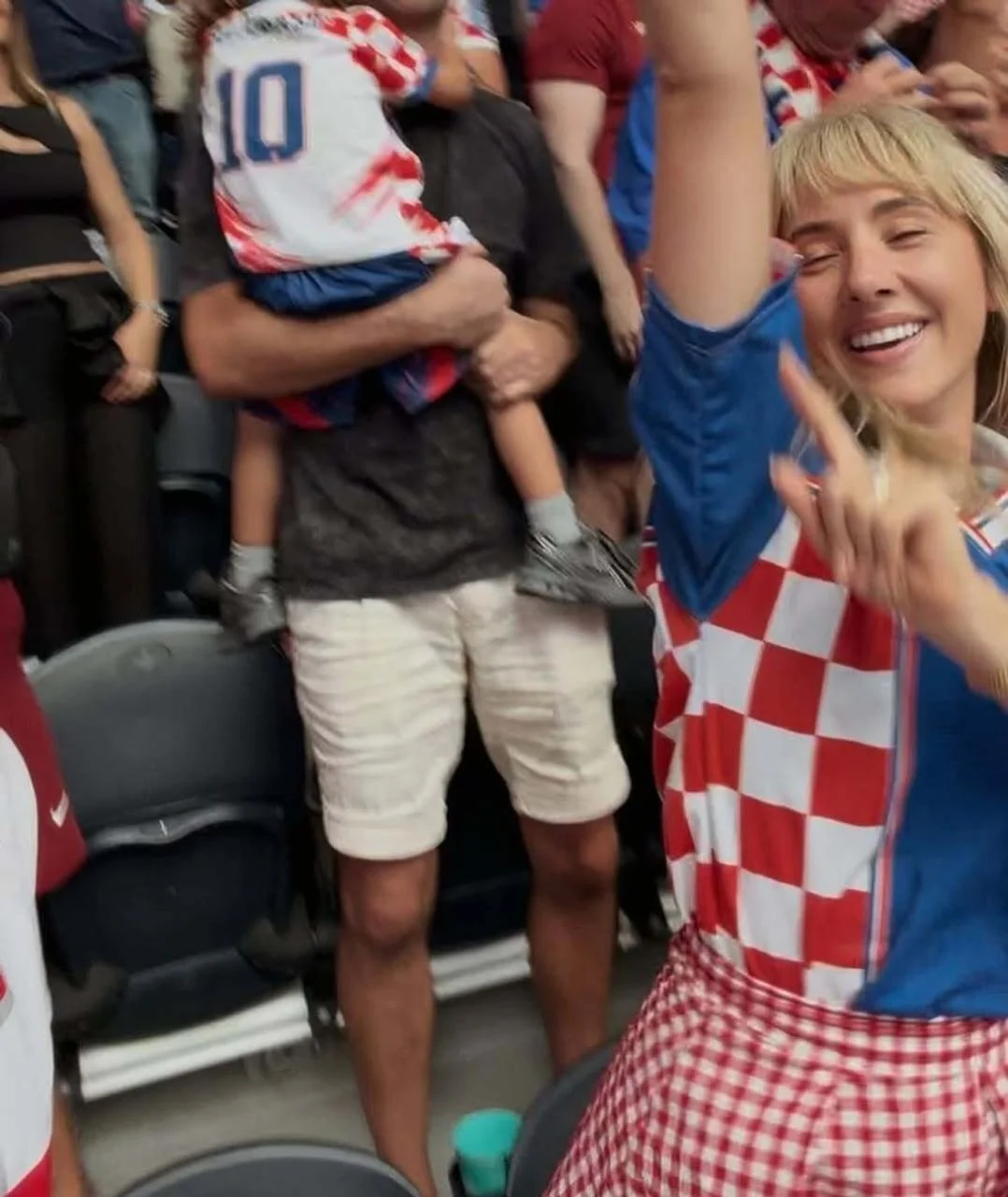 Nasmijana plavokosa žena u dresu Hrvatske s podignutom rukom