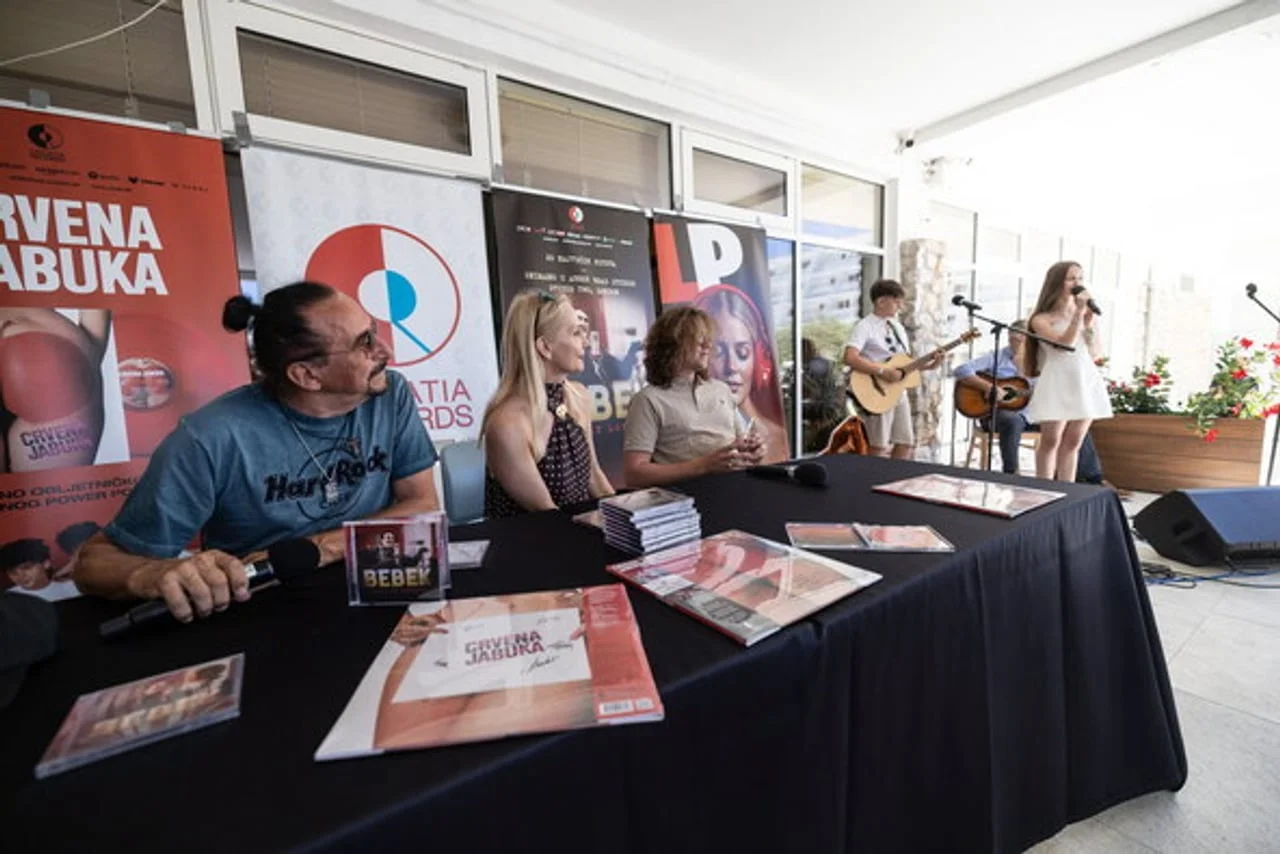 Bebek i pratnja za stolom s promotivnim materijalima albuma
