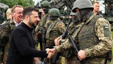 Volodimir Zelenski u crnoj majici rukuje se s ukrajinskim vojnikom u punoj opremi