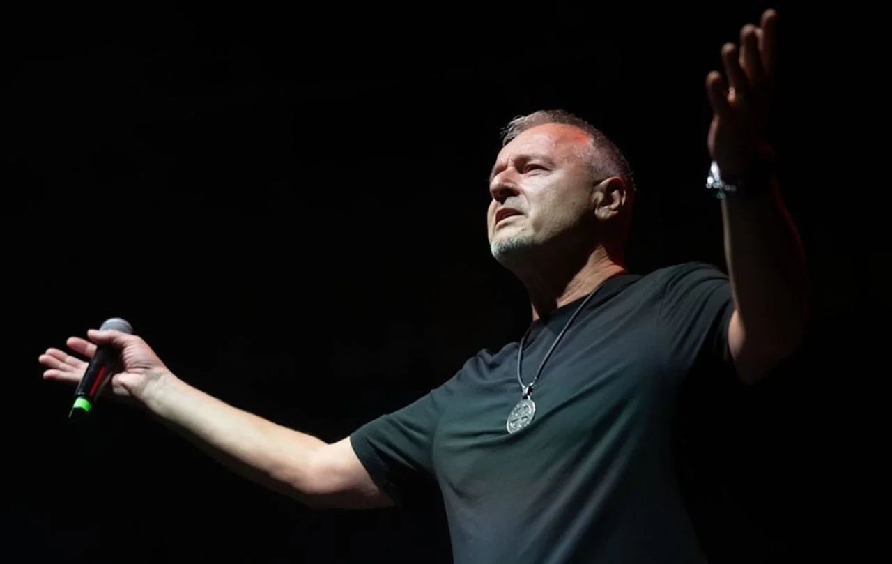 Pjevač Thompson s raširenim rukama i mikrofonu