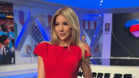 Plavokosa žena u crvenoj haljini u modernom TV studiju