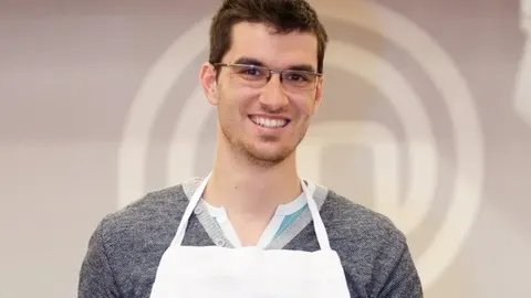 Portret nasmijanog Šime Sušića u bijeloj kuhinjskoj pregači