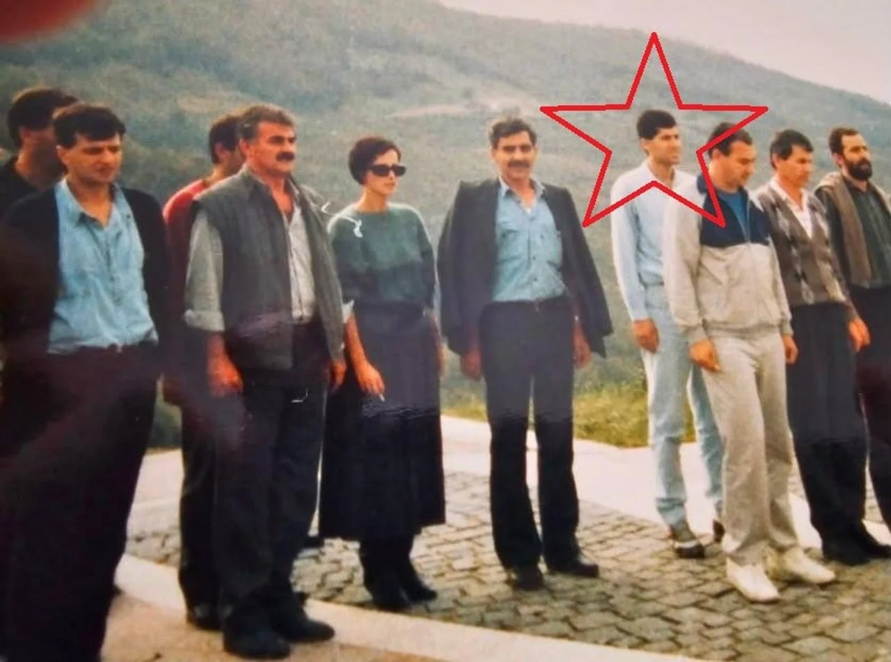 Grupa ljudi stoji u nizu na otvorenom prostoru s crvenom zvjezdom