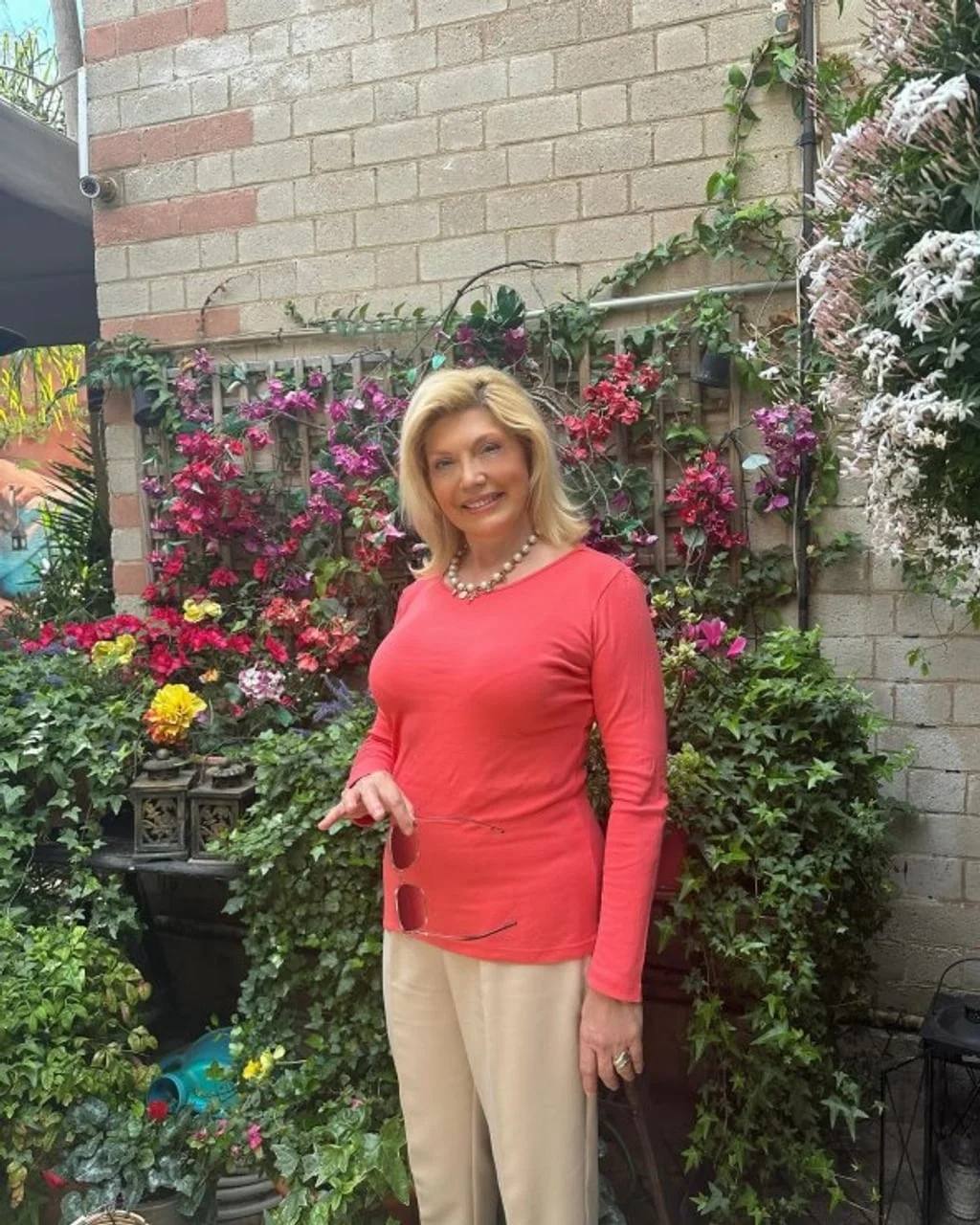 Suzana Mančić u crvenom dresu ispred cvjetnog zida