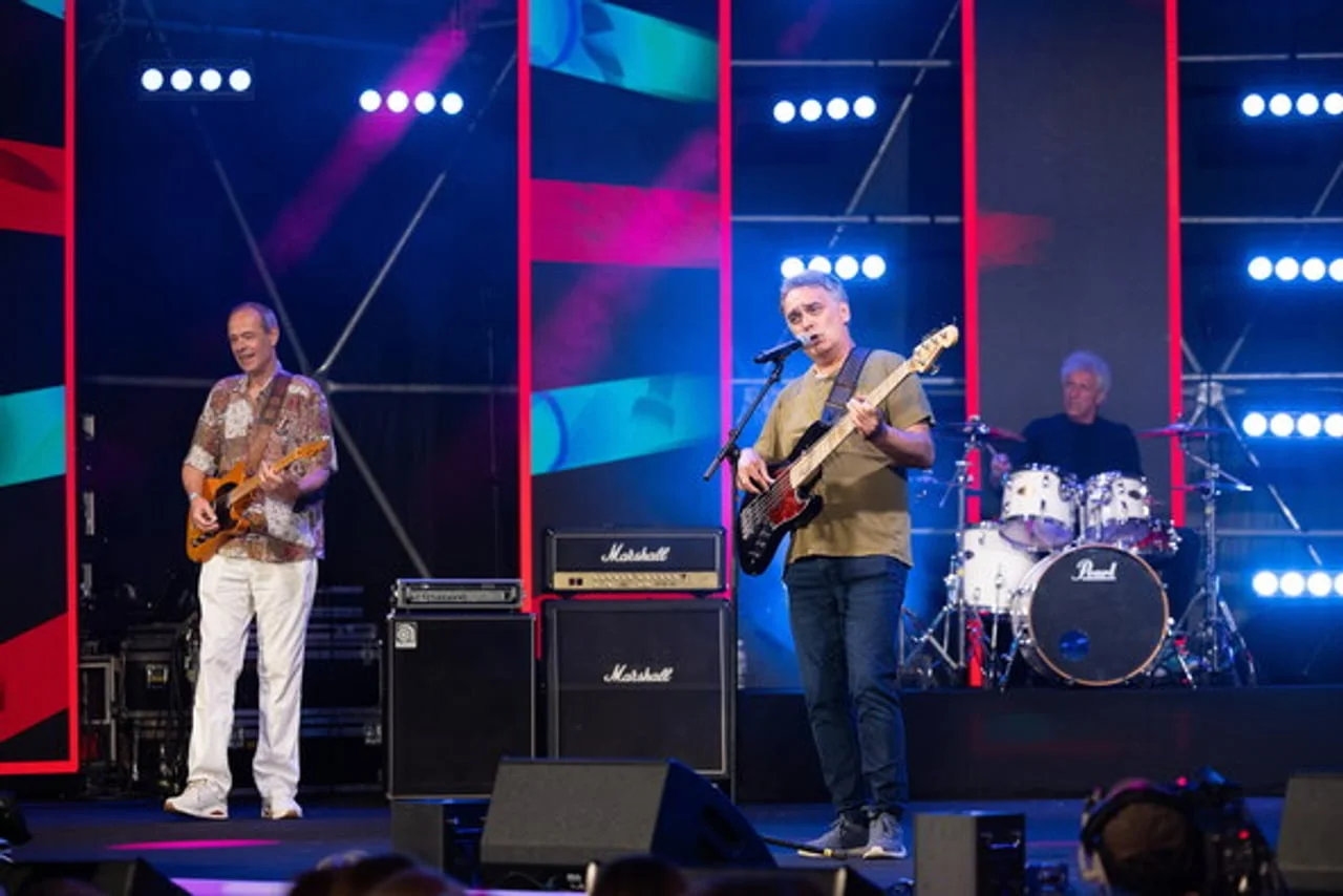 Glazbeni bend s gitaristom i bubnjarom na osvjetljenoj pozornici