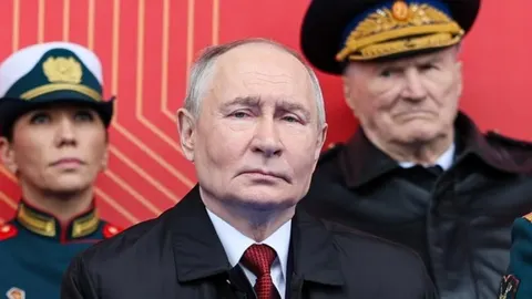Vladimir Putin u crnom kaputu i crvenoj kravati s ozbiljnim izrazom lica