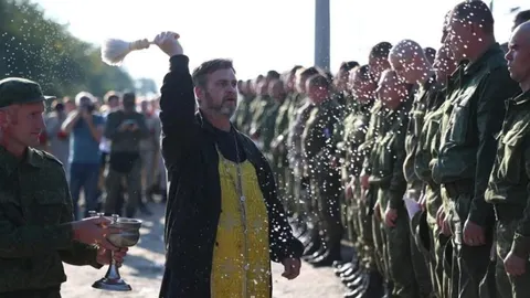 Pravoslavni svećenik prska vodom red vojnika u vojnim uniformama