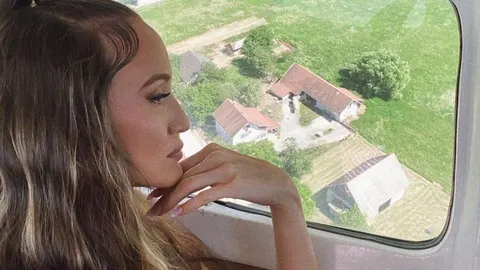 Profil mladog žene s dugačkom smeđom kosom koja gleda kroz prozor