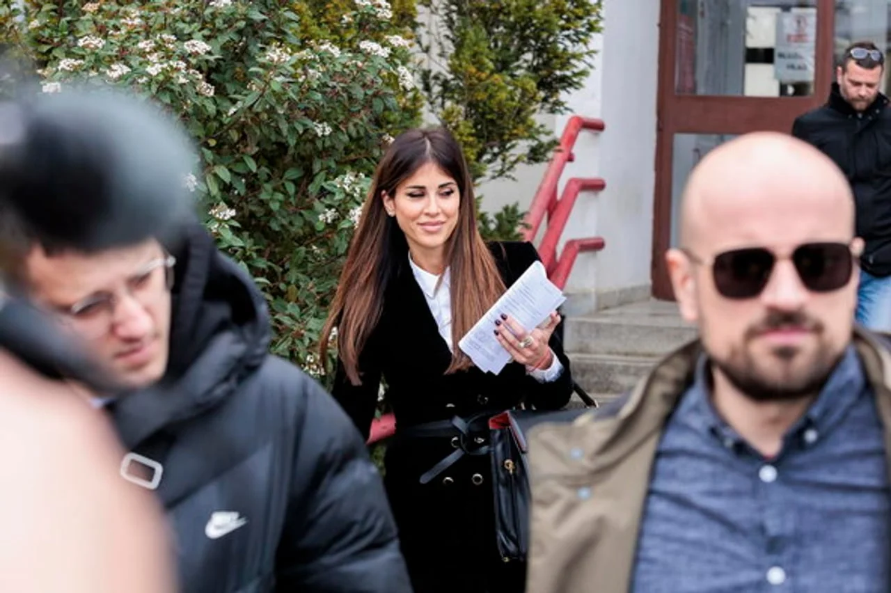 Jovana Puhalo u crnom saku drži papire ispred zgrade