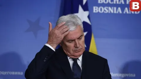 Portret Dragana Čovića u tamnom odijelu koji rukom dodiruje čelo