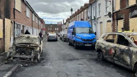 Ulica u Belfastu s izgorjelim automobilima i zatvorenim prozorima