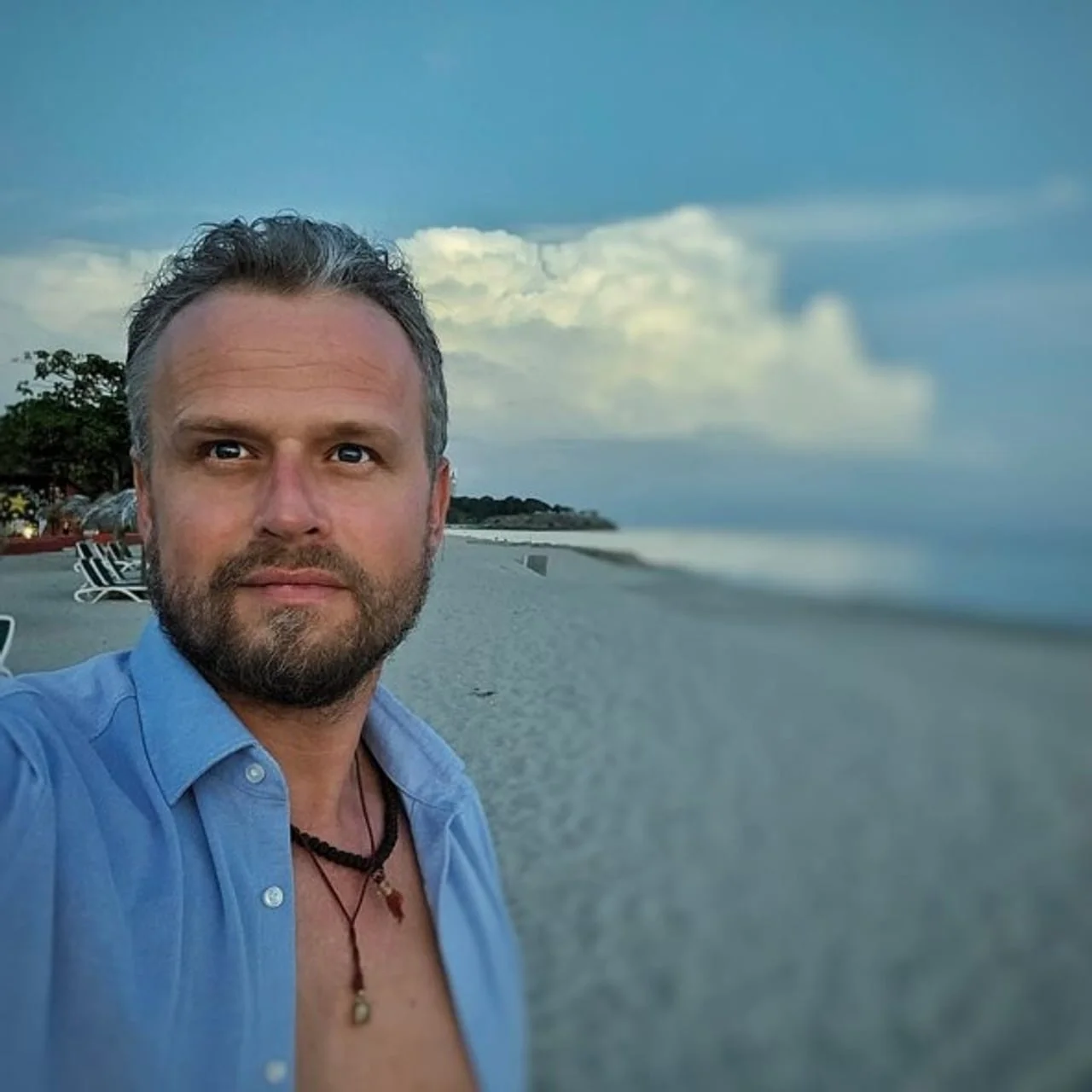 Selfie muškarca s bradom na pješčanoj plaži pored mora