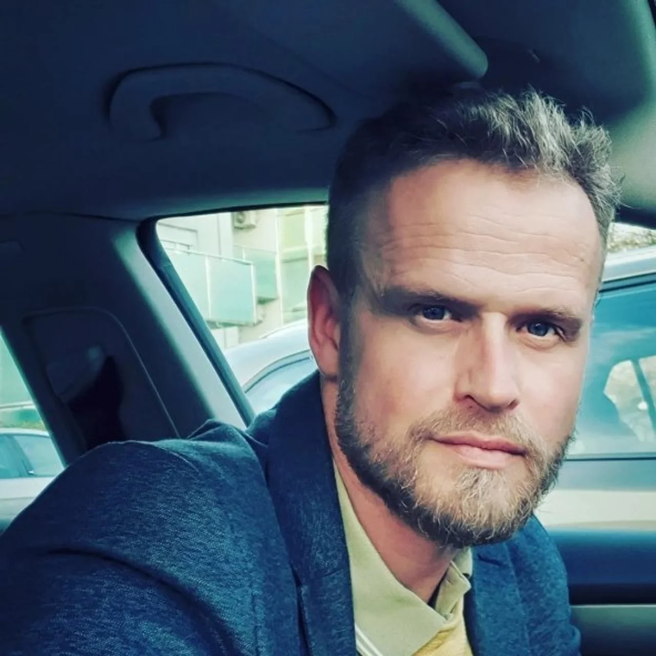 Portret muškarca u plavom saku koji sjedi u automobilu