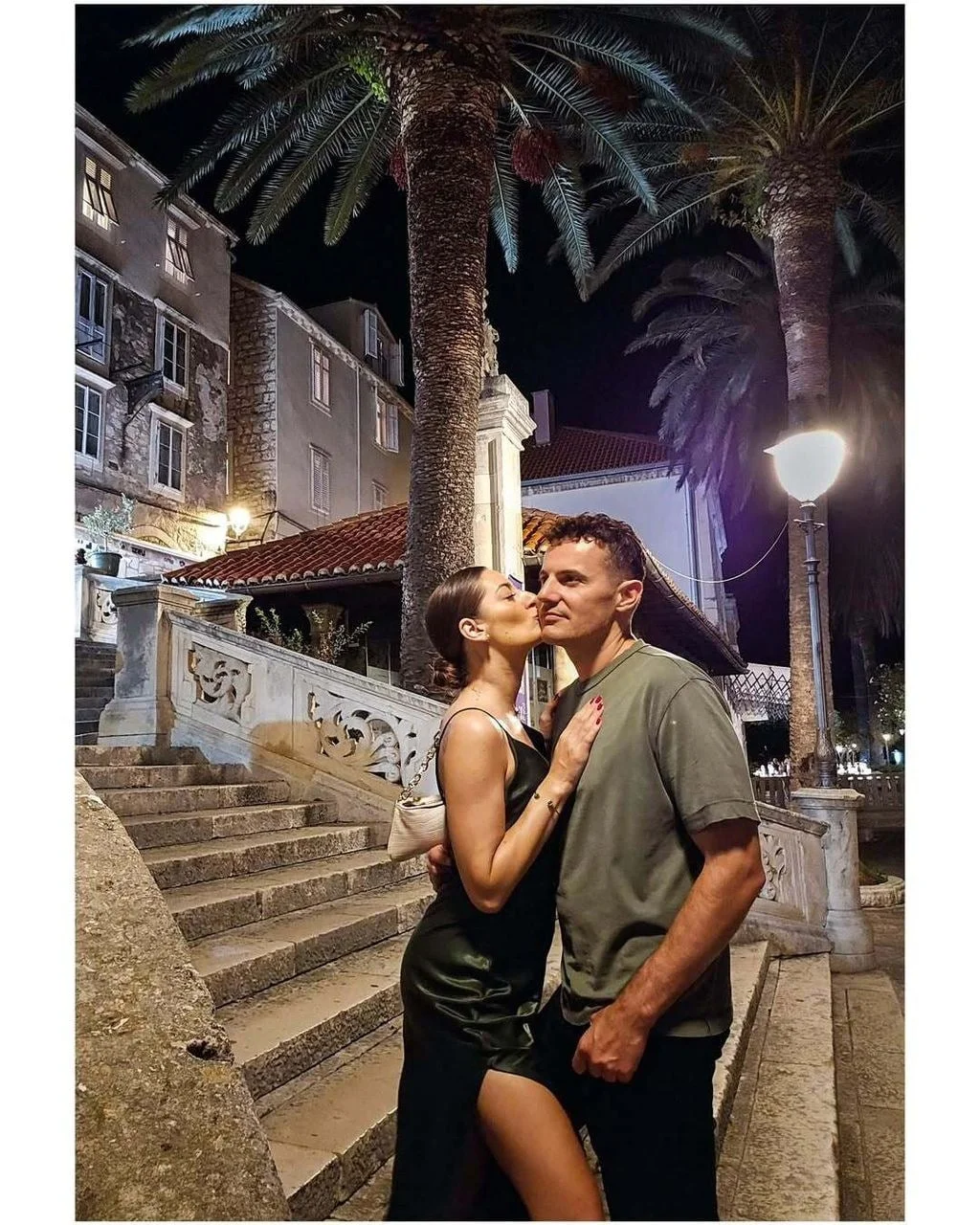 Para se ljubi pokraj starog kamenog stepeništa i palmi noću