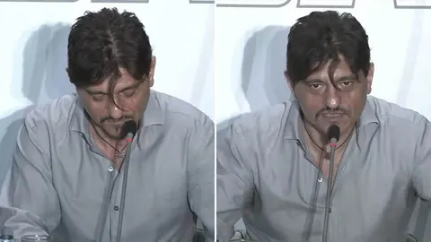 Muškarac u sivoj košulji govori u mikrofon na konferenciji