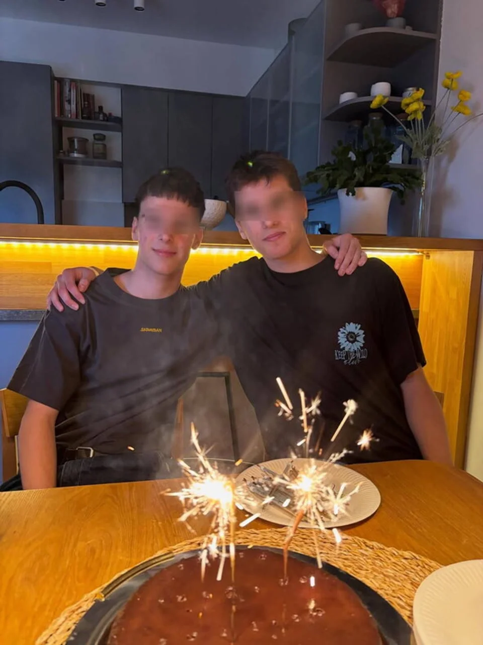 Dva mladića pored rođendanske torte s paljenim bakeljima
