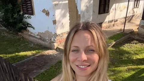 Portret Tene Sakar Vukić ispred stare bijele kuće s oštećenjem fasade