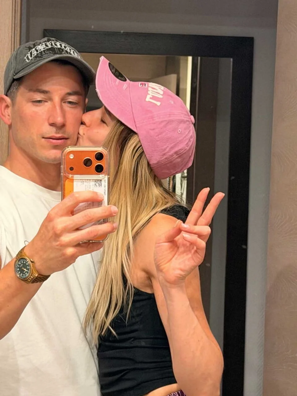 Selfie dvoje mladih ljudi u ogledalu, žena ljubi muškarca u obraz