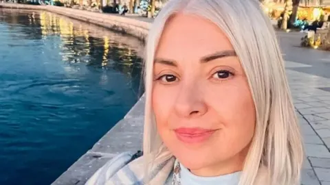 Portret žene plave kose s blagim osmijehom pored vode